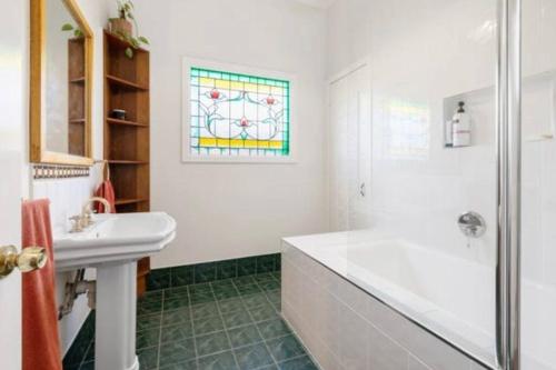 a bathroom with a tub and a sink and a window at Home in Lamington in Kalgoorlie