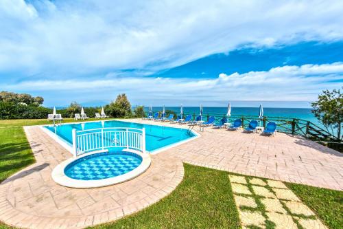 a pool with chairs and the ocean in the background at Loukas Apartments On The Waves in Tragaki