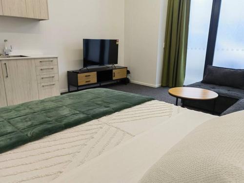 a bedroom with a bed and a tv and a couch at Nestle Brand-new Unit in ChCh CDB in Christchurch