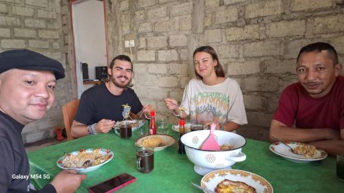 Eine Gruppe von Menschen, die an einem Tisch sitzen und Essen essen. in der Unterkunft Wisma PO'ONG in Ruteng