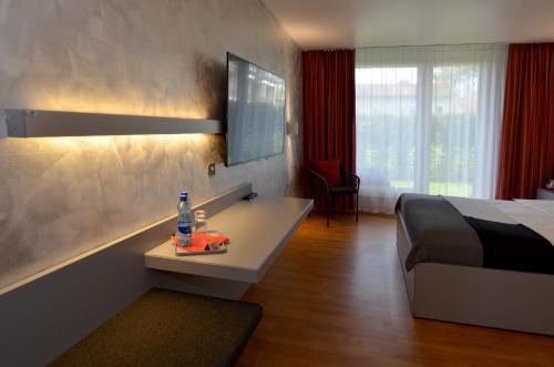 een slaapkamer met een bed en een bureau met een fles water bij Hotel Egerkingen, idealer Zwischenstopp in Egerkingen