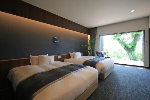 御宿 白金の森 في Kikuchi: غرفة فندقية بسريرين ونافذة كبيرة