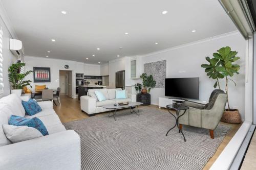 a living room with a couch and a tv at Ocean View Spacious 5BR Retreat for Families in Auckland
