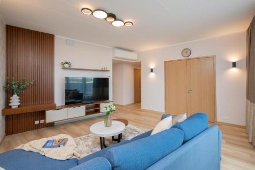 sala de estar con sofá azul y TV en Aatrium Kinnisvara Riia str 22 apartment 80 m2 with 45 m2 terrace, en Tartu