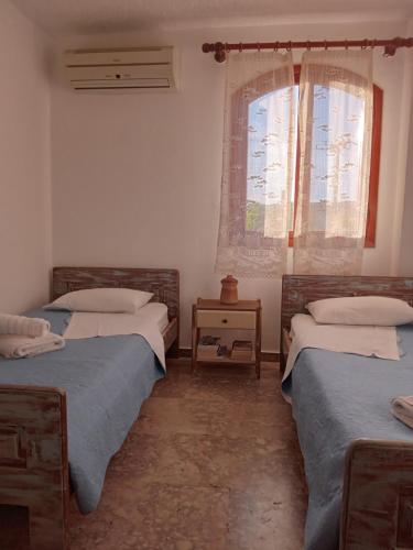 two beds in a room with two windows at Villa Ampelia in Sitia