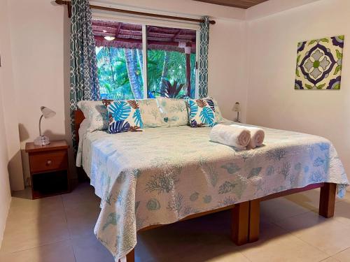 a bedroom with a bed with a window at Palmetto Garden Cottage in Caye Caulker