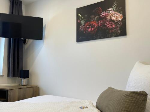 ヘール・グレンツハウゼンにあるApartments im Chateau d'Espritのベッドルーム1室(ベッド1台付)が備わります。壁に花の絵が飾られています。