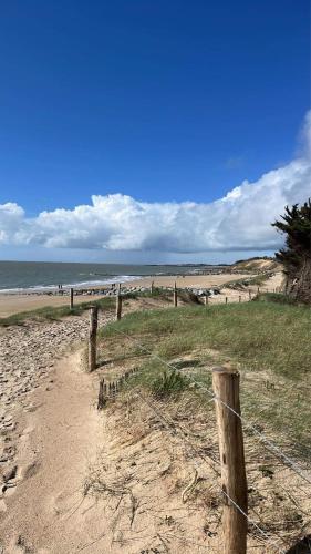 a fence on a beach with the ocean in the background at La Tranquillité in LʼHerbaudière