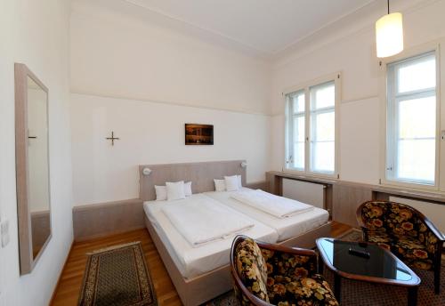 1 dormitorio con 1 cama con 2 sillas y 1 mesa en Gästehaus der Katholischen Akademie in Bayern, en Múnich