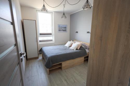 een kleine slaapkamer met een bed en een raam bij Apartament Kapitański in Pogórze