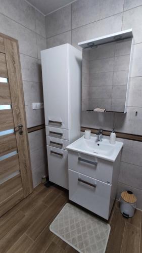 a white bathroom with a sink and a mirror at Apartmán Martina in Trebišov