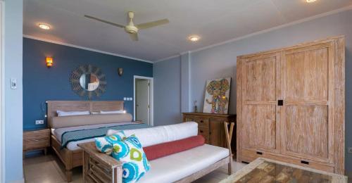 a bedroom with blue walls and a bed and a couch at Beau Vallon Studios - Apartments Vacation Rentals in Victoria