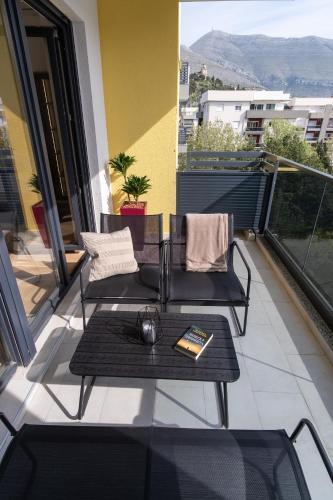 a balcony with two chairs and a table with a book at City Luxury in Trebinje