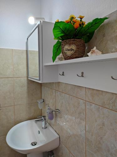 a bathroom with a sink and a vase of flowers on a cabinet at Νέος Πύργος Studio in Neos Pirgos