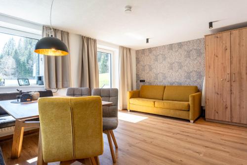 a living room with a table and a yellow couch at Maurig Appartements in Elbigenalp