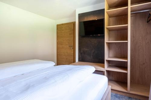 a bedroom with two beds and a tv and shelves at Maurig Appartements in Elbigenalp