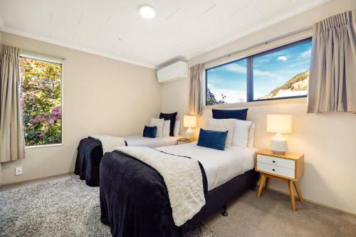 two beds in a room with two windows at Distinctive Stylish and Spacious Family Home in Queenstown