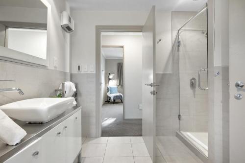 a white bathroom with a sink and a shower at Distinctive Stylish and Spacious Family Home in Queenstown