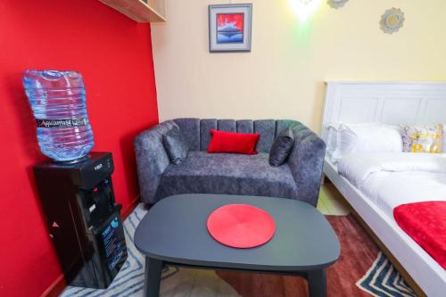 uma sala de estar com um sofá e uma parede vermelha em South Suites Studio apartments South B, Nairobi em Nairobi