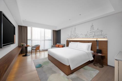 - une chambre avec un lit blanc et une télévision dans l'établissement UrCove Xi'an Hi-Tech Software Park, à Xi'an