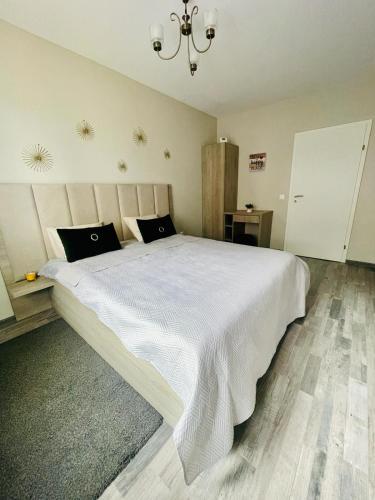 a bedroom with a large white bed with a chandelier at Home Sweet Home in Braşov