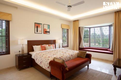 a bedroom with a bed and two windows at StayVista at Silver Oak Farm - Breakfast Included in Bangalore