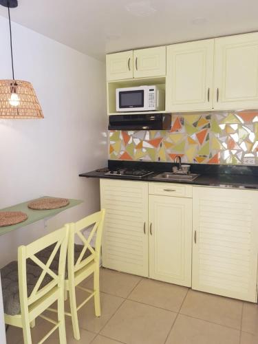 a kitchen with white cabinets and a microwave at Jazmin's Apartment in Oranjestad