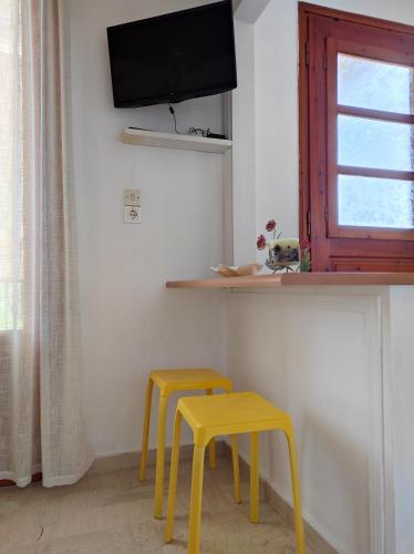 a room with two yellow stools and a tv at Νέος Πύργος Δίκλινο in Néos Pírgos