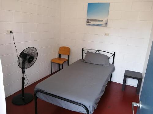 Cette petite chambre comprend un lit et un ventilateur. dans l'établissement Minjerribah Island Accommodation Straddie, à Dunwich