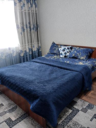 sypialnia z łóżkiem z niebieskim kocem i oknem w obiekcie Квартира w mieście Taraz