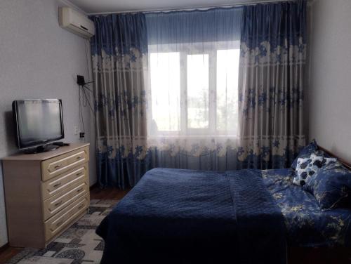 sypialnia z łóżkiem, telewizorem i oknem w obiekcie Квартира w mieście Taraz
