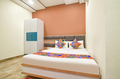 a bedroom with a white bed with colorful pillows at FabHotel SS Blue in Indore