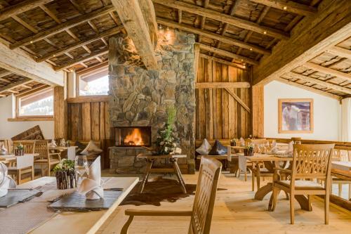 a dining room with a stone fireplace and wooden ceilings at LANIG Hotel Resort&Spa - Wellness und Feinschmeckerhotel - family owned and managed in Oberjoch