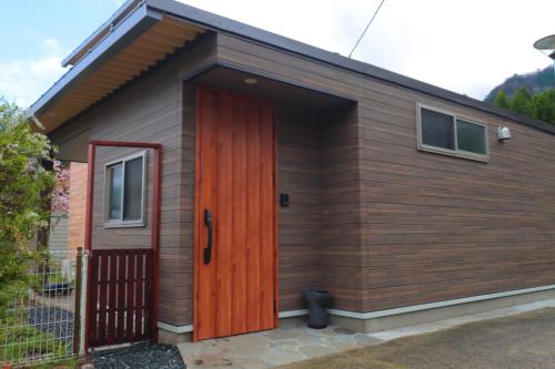 a small cabin with a red door at Tsukitei in Minami Aso