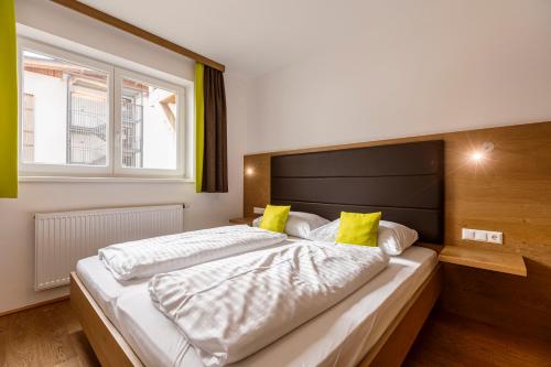 - une chambre avec un grand lit et des oreillers jaunes dans l'établissement Almresort Gartnerkofel Nassfeld by ALPS RESORTS, à Sonnenalpe Nassfeld