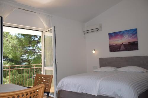 sypialnia z łóżkiem oraz balkon z oknem w obiekcie Apartments Popo w mieście Starigrad-Paklenica