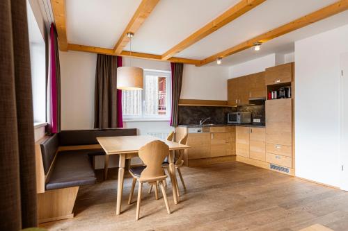 a kitchen with a wooden table and chairs at Almresort Gartnerkofel Nassfeld in Sonnenalpe Nassfeld