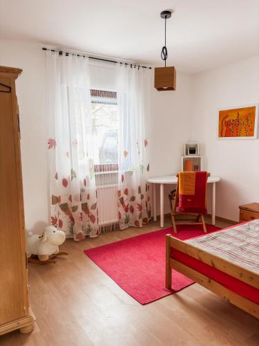 a bedroom with a table and a red chair at Ferienhaus Ebern-Sölln in Ebern