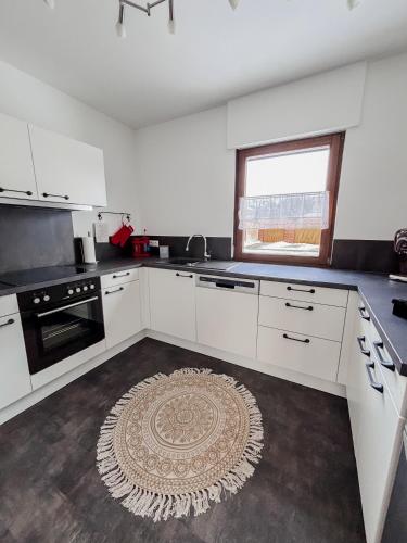 a kitchen with white cabinets and a rug on the floor at Ferienhaus Ebern-Sölln in Ebern