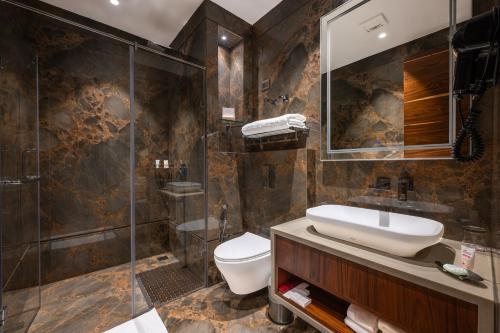 a bathroom with a toilet and a sink and a shower at WelcomHeritage Elysium Resort & Spa in Shimla