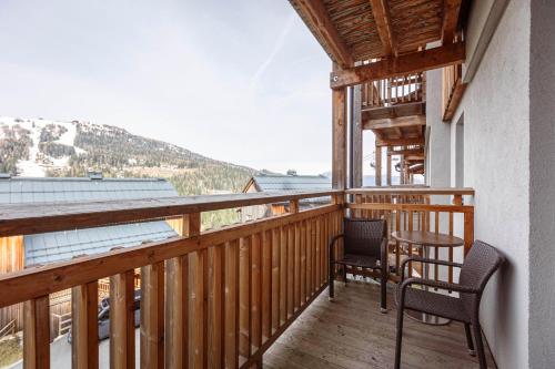 a balcony with two chairs and a table on it at Almresort Gartnerkofel Nassfeld in Sonnenalpe Nassfeld