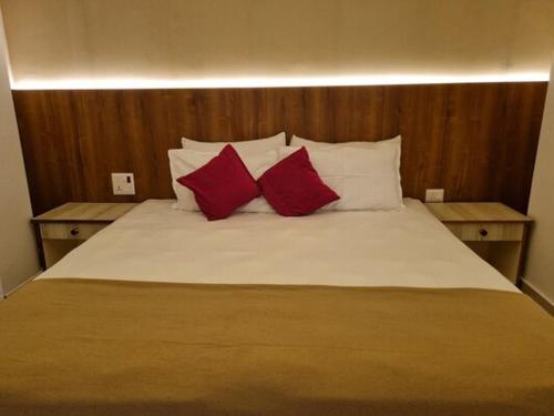 uma cama com duas almofadas vermelhas em cima em TANTRA BOUTIQUE HOTEL em Imphal