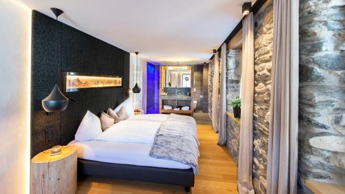 a bedroom with a large white bed and a stone wall at LARET private Boutique Hotel - Adults only in Samnaun