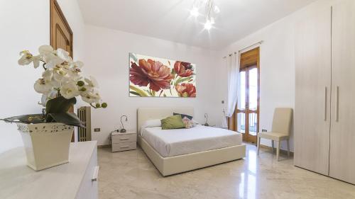 a white bedroom with a bed and a vase of flowers at Appartamento Stapane by Palazzo Stapane in Galatone