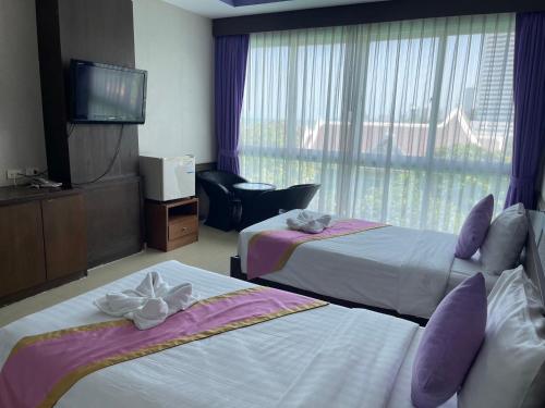 a hotel room with two beds and a television at The Sand Beach Pattaya in Na Jomtien