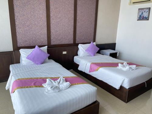 two beds in a hotel room with purple and white pillows at The Sand Beach Pattaya in Na Jomtien