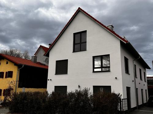 een wit huis met zwarte ramen en een bewolkte lucht bij Ferienziel Wibmer in Landsberg am Lech