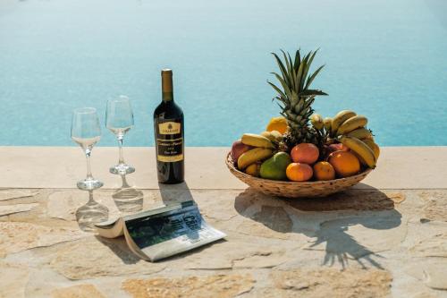 a table with a bowl of fruit and a bottle of wine at Villa Thea in Mochlos
