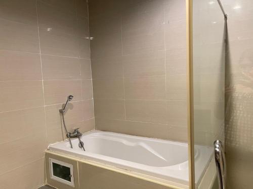a bathroom with a bath tub with a shower at The Sand Beach Pattaya in Na Jomtien
