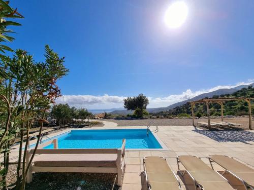 een zwembad met stoelen en de oceaan op de achtergrond bij Magical Crete Villa| Villa Giorgos | Beautiful Sea & Landmark views | Terrace & Private Pool | 2 Bedrooms | Agia Galini in Agia Galini